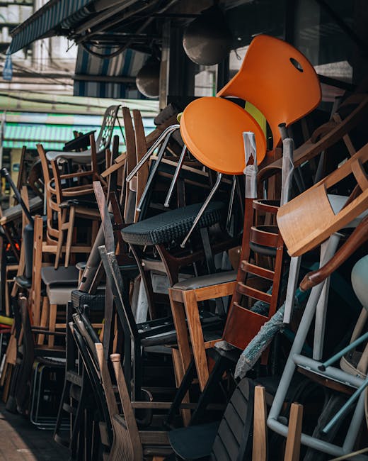 Inside a room during a home relocation, there are three large cardboard boxes stacked in the corner, with one box slightly smaller and placed on top of two larger boxes. To the right of the boxes, the